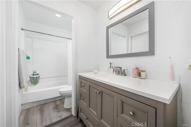 bathroom with toilet,  shower combination, wood finished floors, and vanity