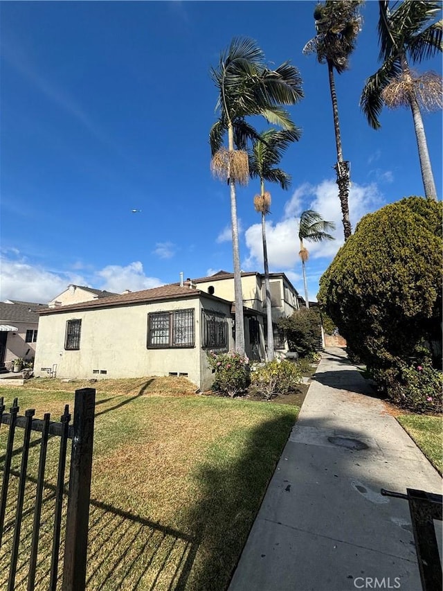 view of home's exterior featuring a yard, fence, and stucco siding