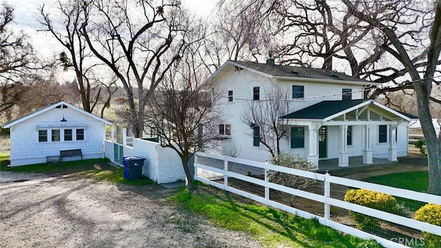 view of front of home with driveway, a chimney, and fence