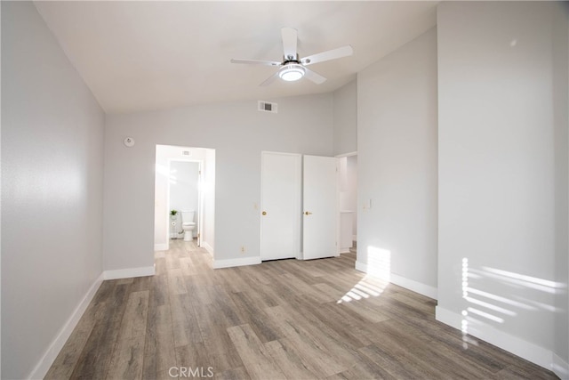 unfurnished bedroom featuring visible vents, connected bathroom, wood finished floors, high vaulted ceiling, and baseboards