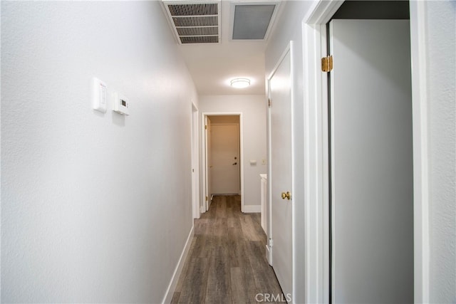 hall featuring dark wood-type flooring, visible vents, and baseboards