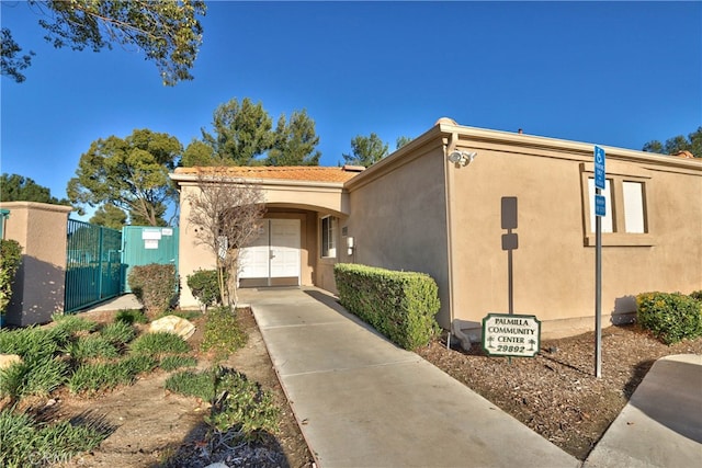 view of front of property featuring driveway, a garage, fence, and stucco siding