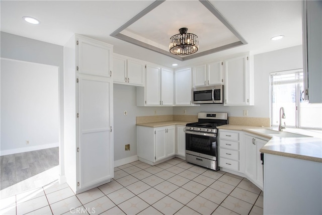 kitchen featuring white cabinetry, appliances with stainless steel finishes, a raised ceiling, and light countertops