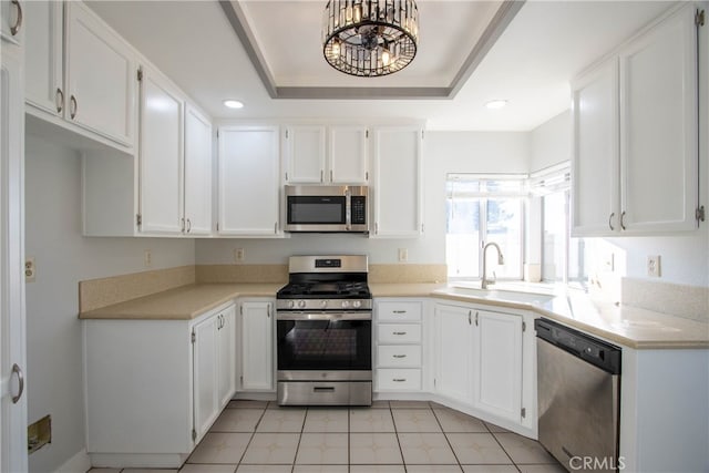 kitchen featuring white cabinetry, stainless steel appliances, light countertops, and a raised ceiling