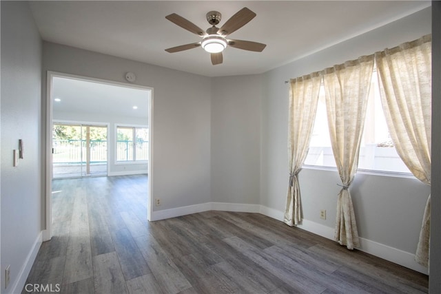 unfurnished room featuring dark wood-style floors, ceiling fan, and baseboards