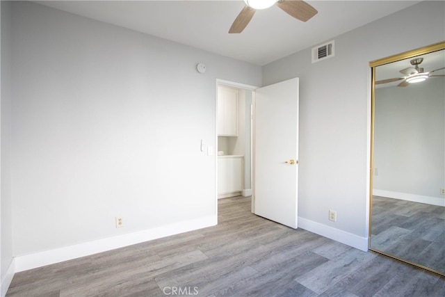 unfurnished bedroom featuring baseboards, visible vents, ceiling fan, light wood-style floors, and a closet