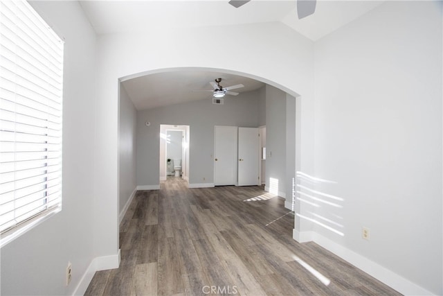 interior space with baseboards, arched walkways, lofted ceiling, ceiling fan, and dark wood-type flooring