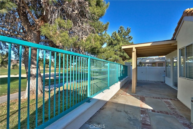 view of gate with a patio area, fence, and a yard