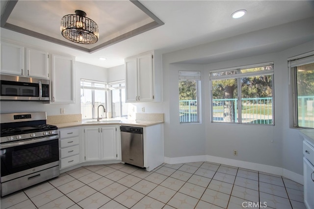 kitchen with light countertops, appliances with stainless steel finishes, a sink, and white cabinets