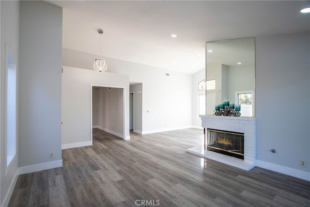 unfurnished living room with high vaulted ceiling, dark wood-type flooring, a brick fireplace, and baseboards