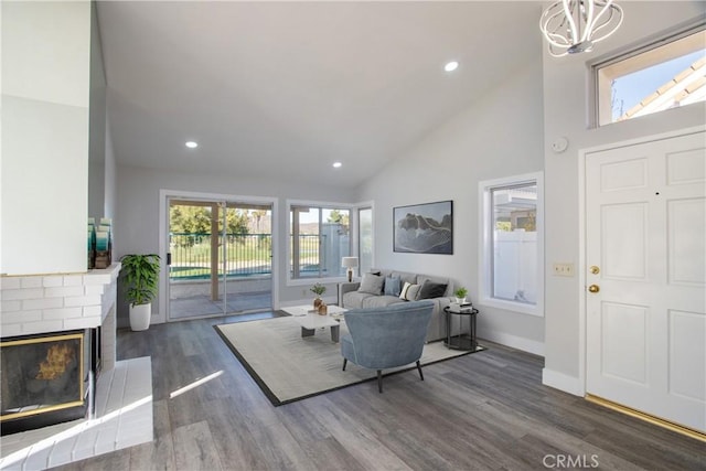 living room featuring high vaulted ceiling, a wealth of natural light, a fireplace, and dark wood finished floors