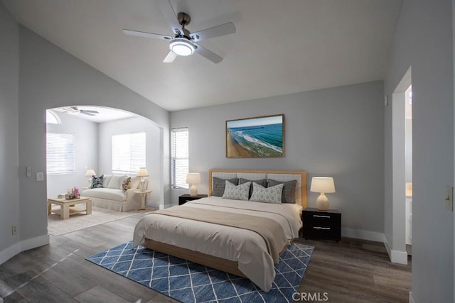 bedroom with lofted ceiling, dark wood finished floors, arched walkways, and baseboards