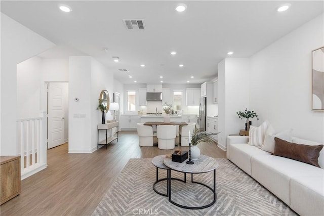 living area with light wood-type flooring, visible vents, and recessed lighting