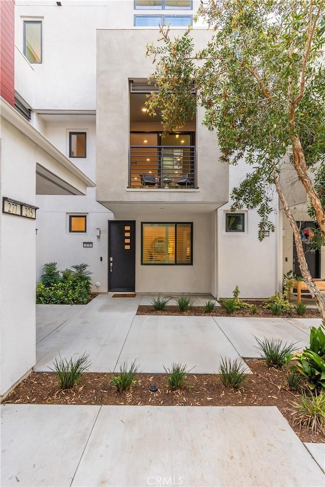 view of exterior entry featuring a balcony and stucco siding