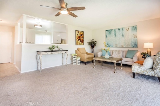 carpeted living area with ceiling fan and baseboards