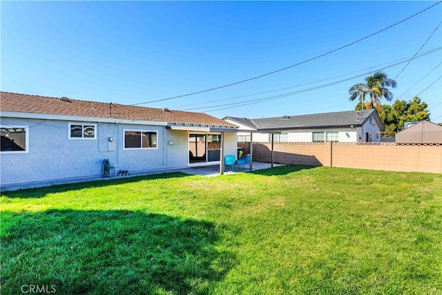 back of property with stucco siding, a fenced backyard, a patio, and a yard