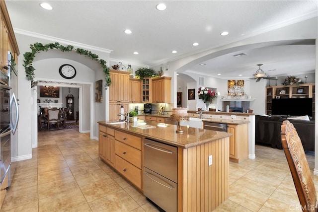 kitchen featuring a center island with sink, arched walkways, glass insert cabinets, open floor plan, and a peninsula