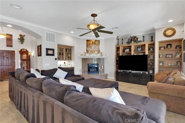 living area featuring a high end fireplace, visible vents, arched walkways, ornamental molding, and recessed lighting