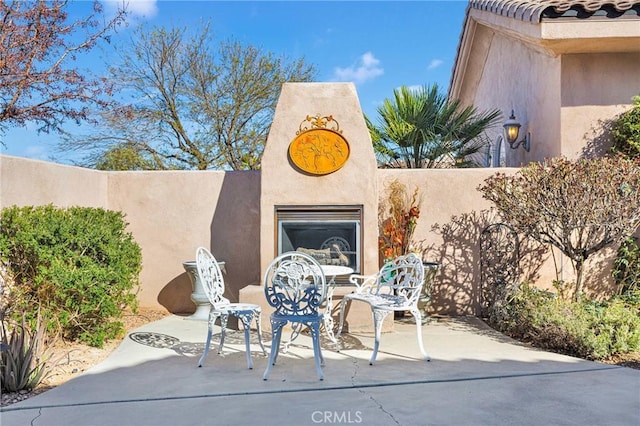 view of patio featuring an outdoor fireplace and fence