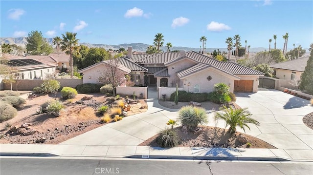 mediterranean / spanish-style house featuring stucco siding, fence, a mountain view, a garage, and driveway