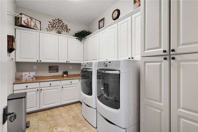 laundry room featuring light tile patterned floors, washer and clothes dryer, and cabinet space