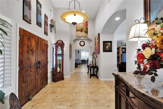 entrance foyer featuring arched walkways, a towering ceiling, and baseboards