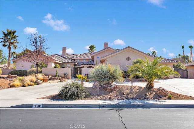 mediterranean / spanish home with concrete driveway, fence, a tiled roof, and stucco siding