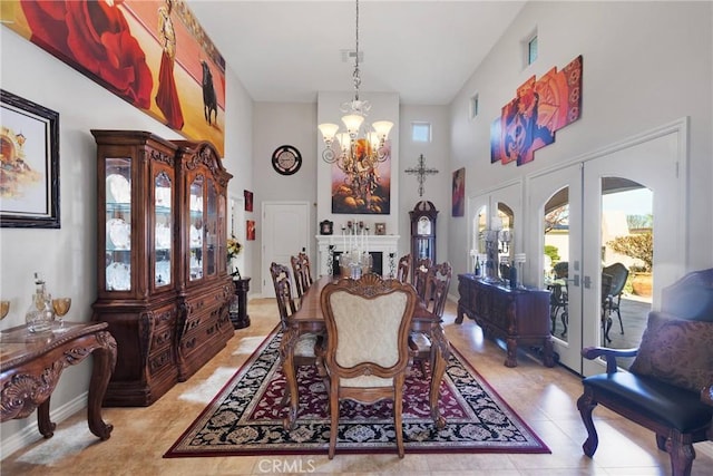 dining area featuring visible vents, a high ceiling, french doors, a fireplace, and a notable chandelier