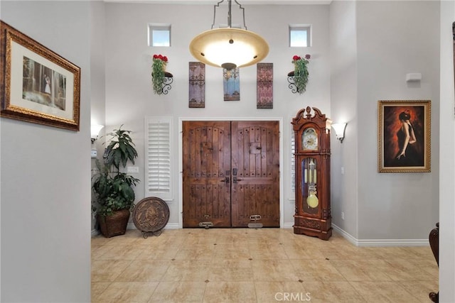 foyer with a healthy amount of sunlight, a towering ceiling, and baseboards