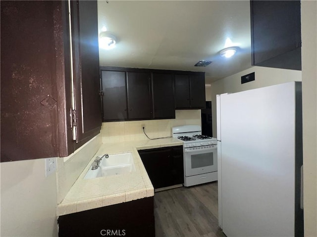 kitchen with dark wood-style floors, light countertops, visible vents, a sink, and white appliances