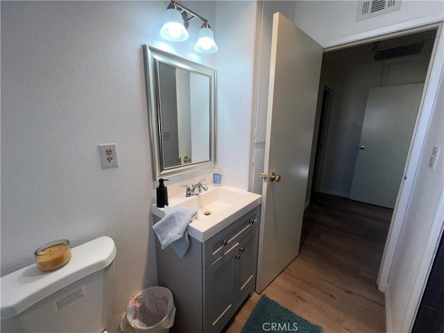 bathroom featuring visible vents, vanity, toilet, and wood finished floors