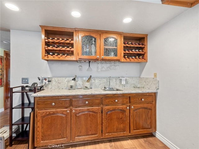 bar featuring indoor wet bar, recessed lighting, light wood-style flooring, a sink, and baseboards