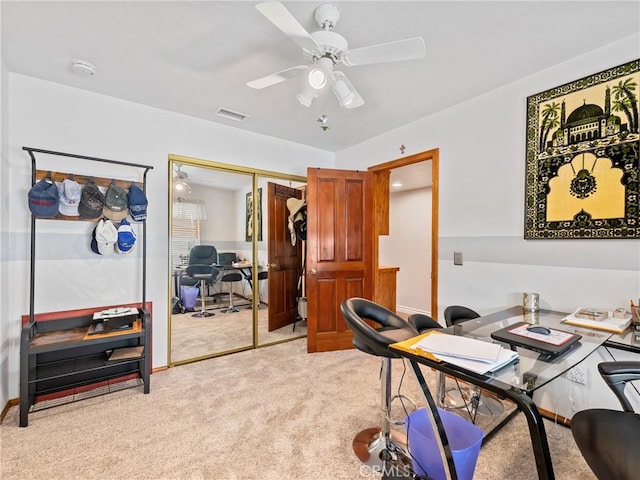 home office with a ceiling fan, light carpet, visible vents, and baseboards