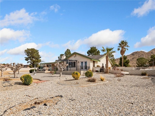 view of front facade featuring french doors, fence, a mountain view, and stucco siding