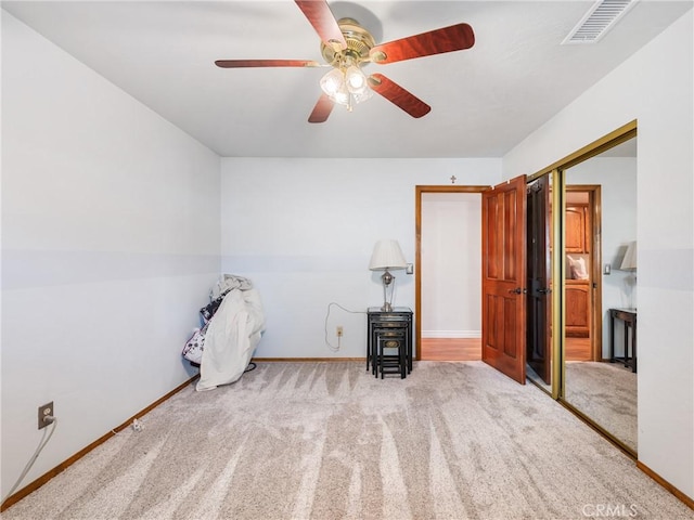 interior space with baseboards, ceiling fan, visible vents, and light colored carpet