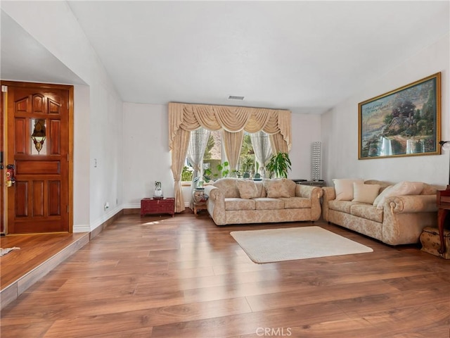 living room with wood finished floors, visible vents, and baseboards