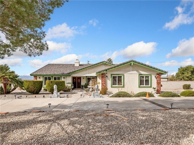 ranch-style house with stucco siding, a chimney, fence, and a patio