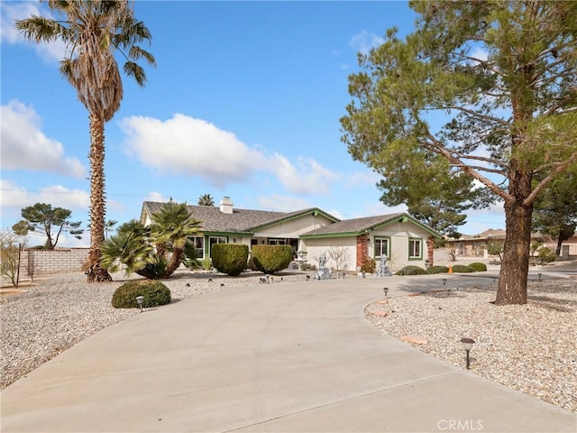 ranch-style house with concrete driveway, a chimney, and fence