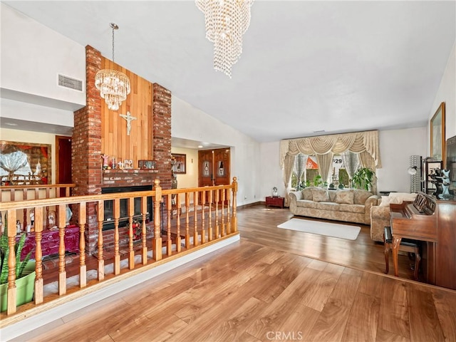 living room with high vaulted ceiling, wood finished floors, visible vents, baseboards, and an inviting chandelier