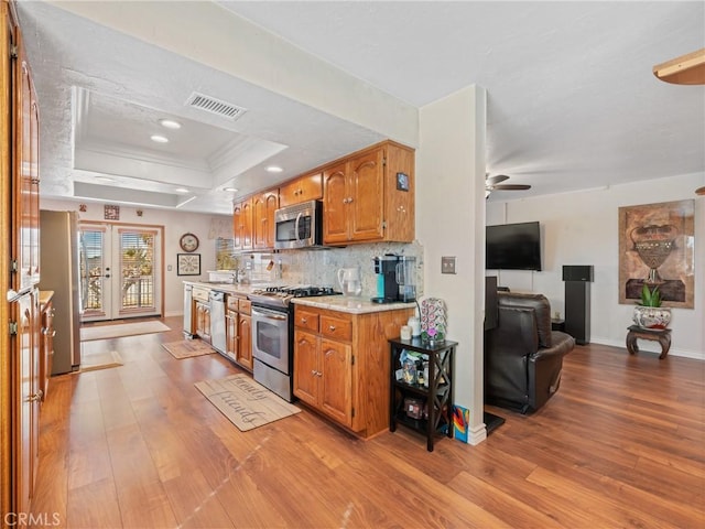 kitchen with visible vents, light countertops, appliances with stainless steel finishes, tasteful backsplash, and a raised ceiling