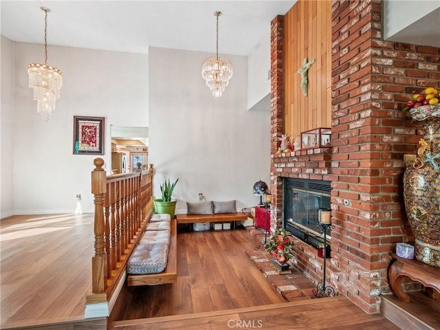 living room with a fireplace, wood finished floors, a towering ceiling, and a notable chandelier