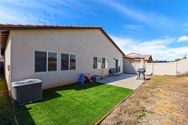 rear view of house featuring stucco siding, a lawn, a patio area, cooling unit, and a fenced backyard