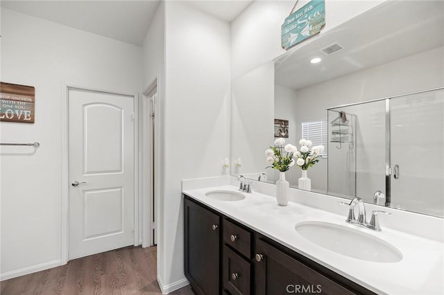 full bathroom featuring double vanity, wood finished floors, a sink, and visible vents