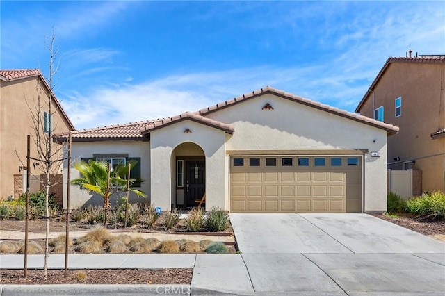 mediterranean / spanish-style home with a garage, a tile roof, concrete driveway, and stucco siding