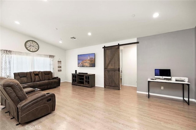 living area with light wood finished floors, a barn door, and visible vents