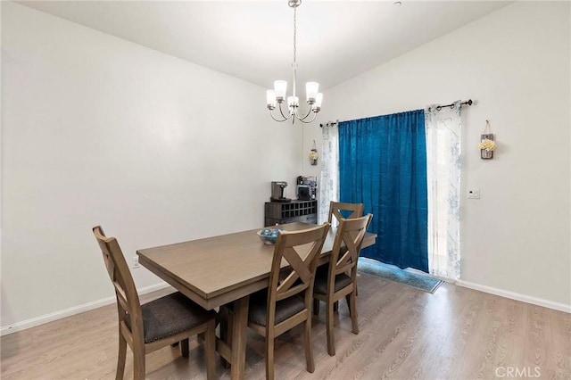 dining space featuring light wood-style flooring, baseboards, and a notable chandelier