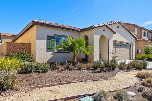 mediterranean / spanish house featuring concrete driveway, a tile roof, an attached garage, and stucco siding