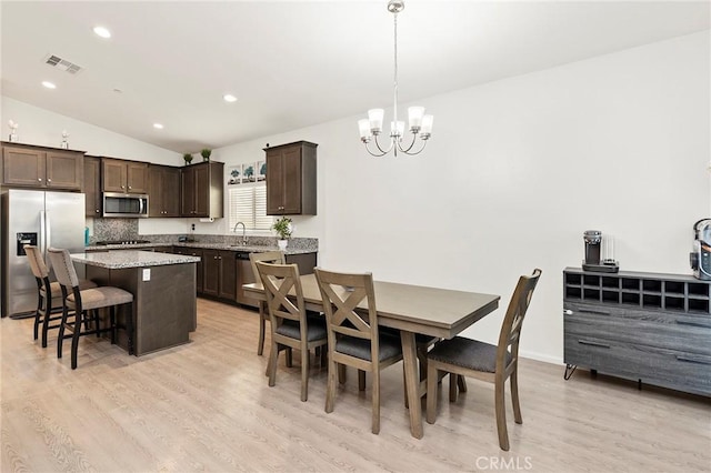 dining room featuring visible vents, lofted ceiling, light wood-type flooring, a chandelier, and recessed lighting