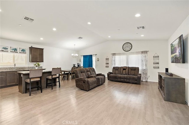 living area featuring lofted ceiling, visible vents, and light wood finished floors