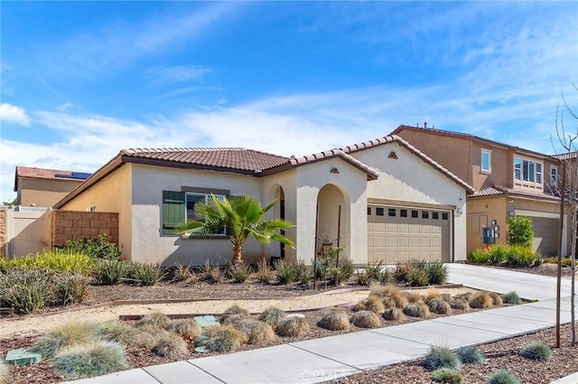 mediterranean / spanish house featuring a garage, concrete driveway, a tile roof, and stucco siding